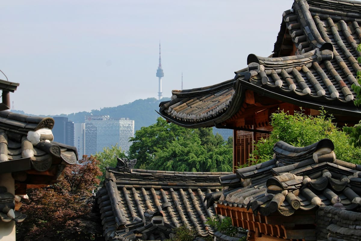 Traditional hanok rooftops below a Seoul mountain